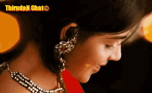a close up of a woman wearing earrings and a red saree