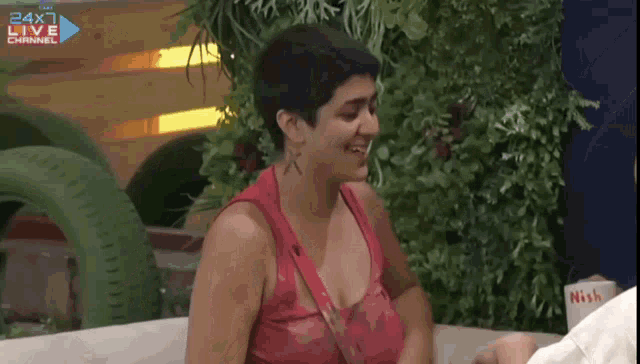 a woman in a red tank top is laughing in front of a 24x1 live channel sign
