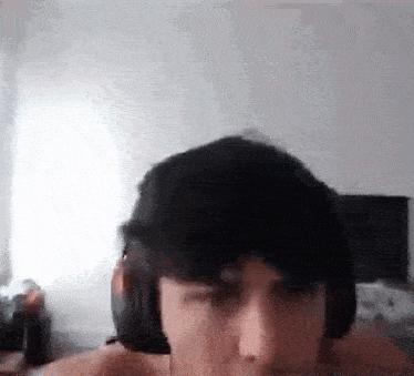 a man wearing headphones is making a funny face while sitting on a bed .
