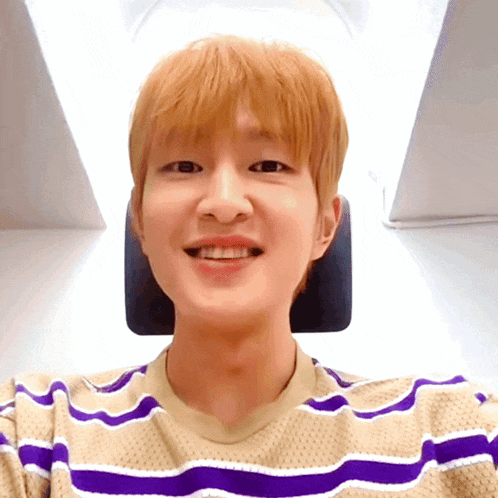 a young man with blonde hair is wearing a striped shirt
