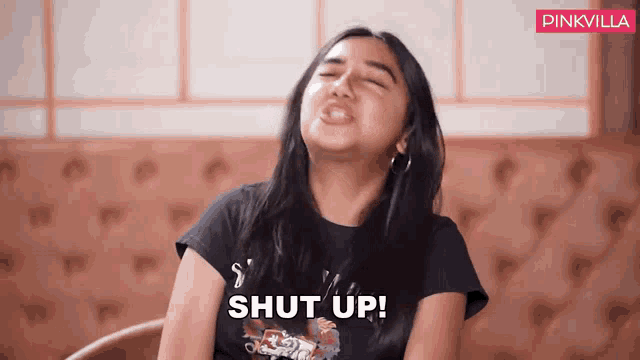 a woman is sitting in a chair with her mouth open and says shut up .