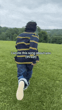 a person in a striped shirt is walking through a grassy field