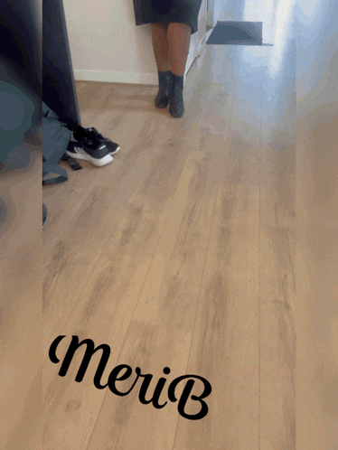 a woman in a black dress is walking down a hallway with the name meriu written on the floor