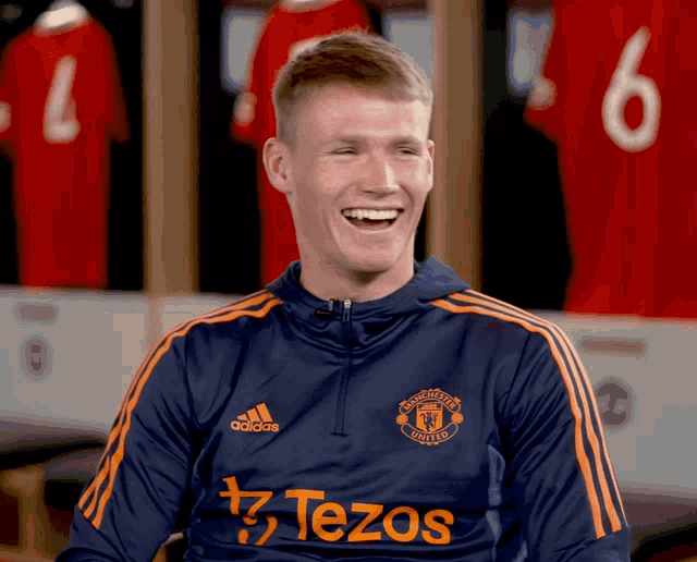 a man wearing a manchester united shirt laughs