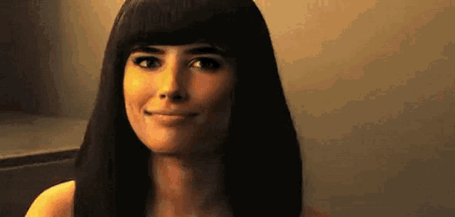 a woman with long black hair and a fringe is smiling .