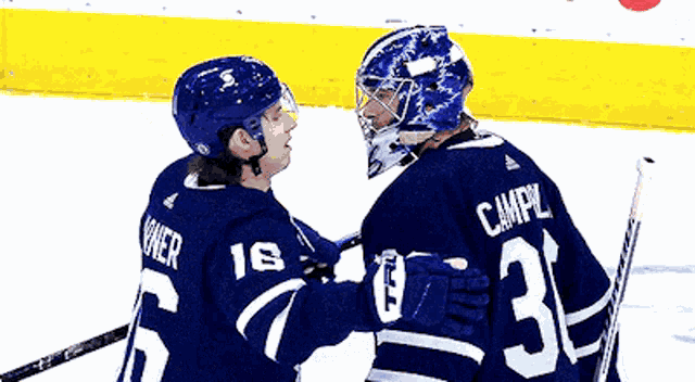 a hockey player wearing a number 19 jersey talks to another player wearing a number 31 jersey