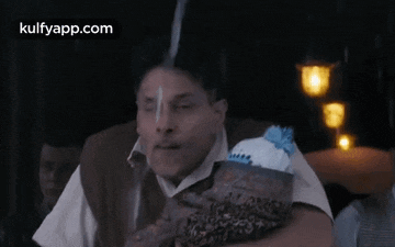 a man is sitting at a table with a bag of tissues in his hand and making a funny face .
