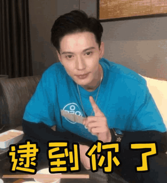 a man in a blue shirt is sitting at a table with chinese writing on the table