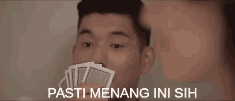 a young man is holding a bunch of playing cards in his hand .