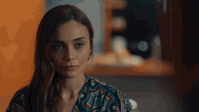 a woman in a colorful shirt looks to the side