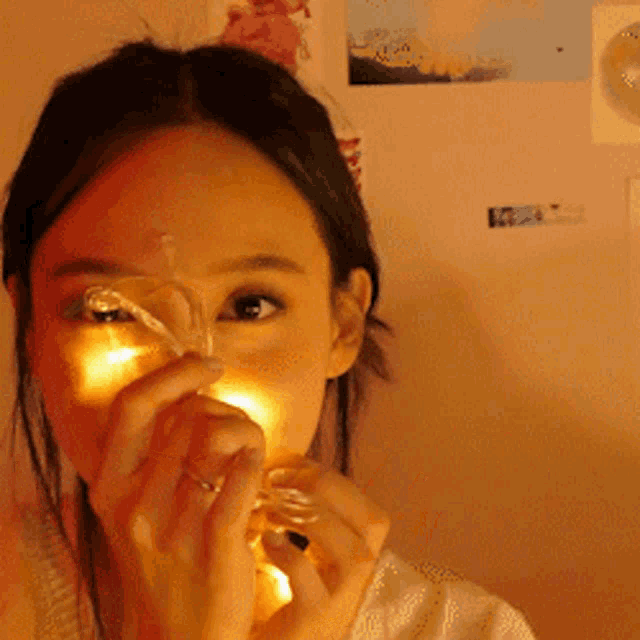 a woman with a ring on her finger is holding a light bulb in front of her face