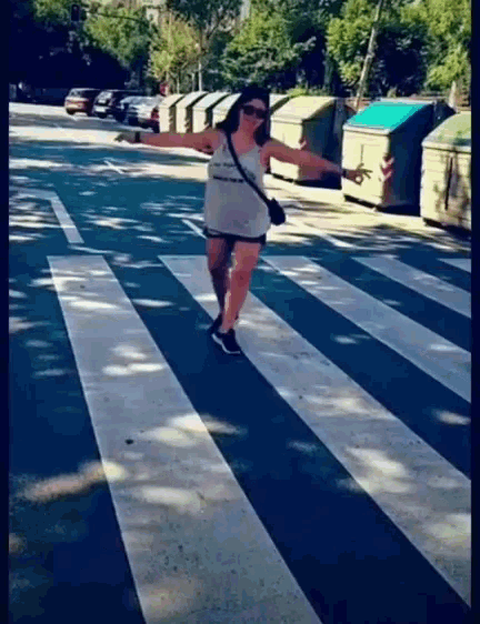 a woman is crossing a zebra crossing with her arms outstretched