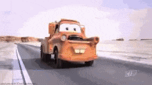 a tow truck from cars is driving down a desert road .
