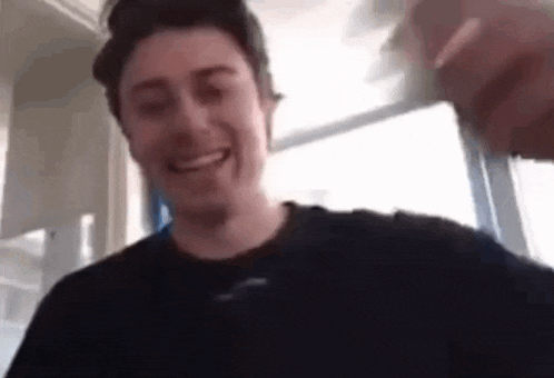 a man in a black shirt is smiling while holding a glass of water .
