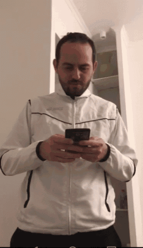 a man in a white jacket looks at his cell phone