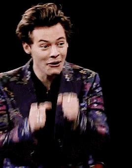 a man wearing a colorful jacket and a black shirt smiles