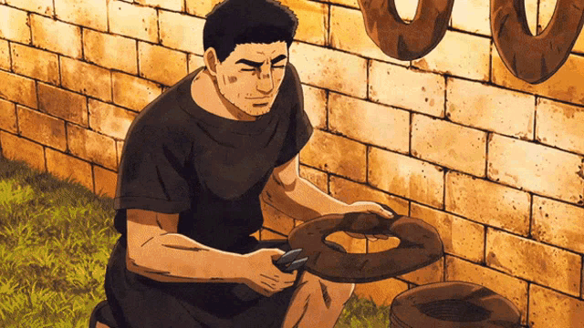 a man in a black shirt is kneeling in front of a brick wall holding a pair of scissors