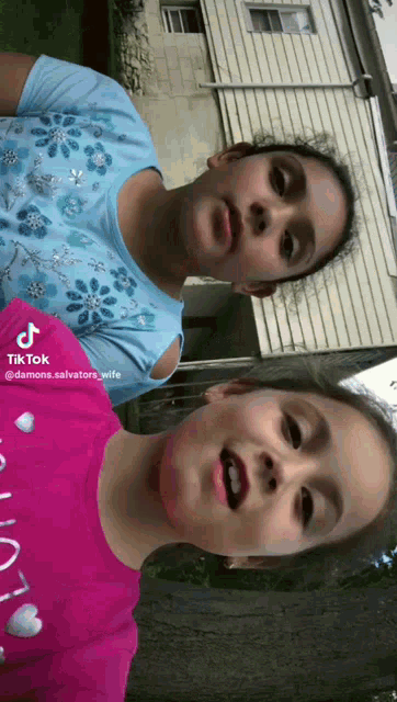 two girls are standing next to each other and one has a tiktok sticker on her shirt