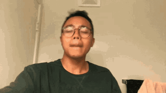 a man in a green shirt is making a funny face with his mouth open .