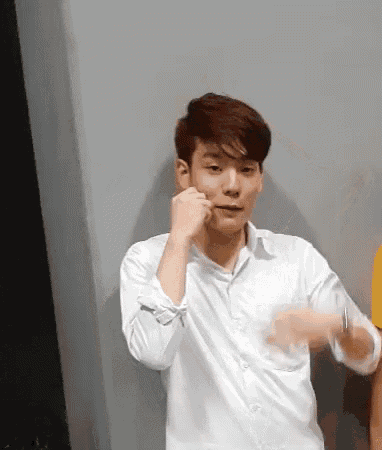 a young man in a white shirt is making a funny face .