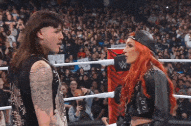 a man and a woman are standing in a wrestling ring looking at each other .