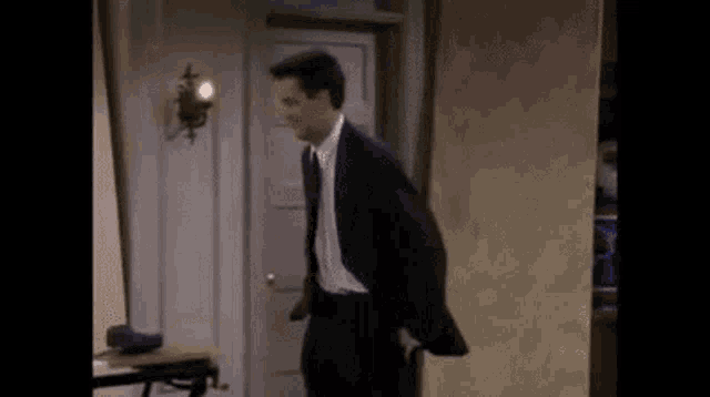 a man in a suit and tie is walking through a doorway holding an umbrella .