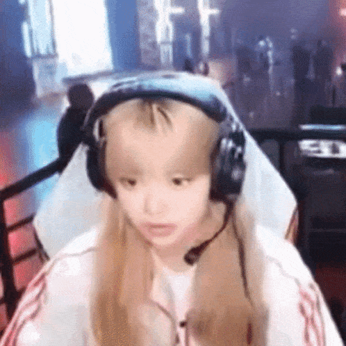 a girl wearing headphones and a microphone is sitting in a gaming chair .