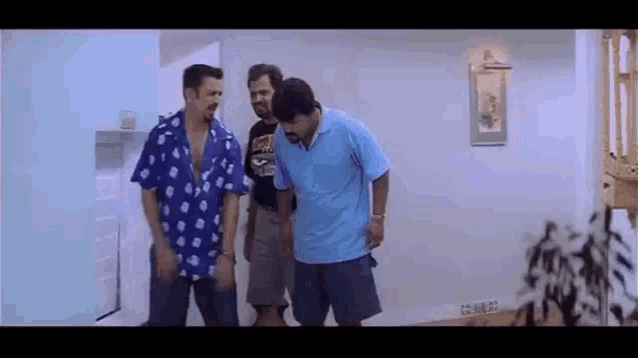 three men are standing in a room talking to each other .