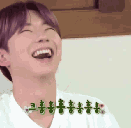 a young man with purple hair is laughing with his mouth open .