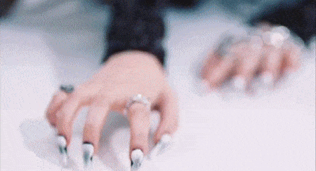 a close up of a woman 's hand with long nails and a ring on her finger .