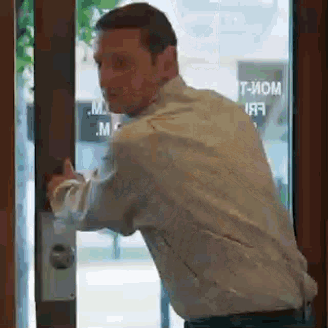 a man in a white shirt is opening a door