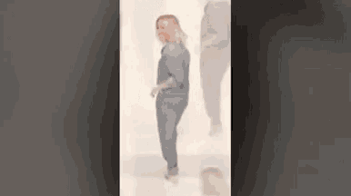 a blurry picture of a woman standing in front of a wall .