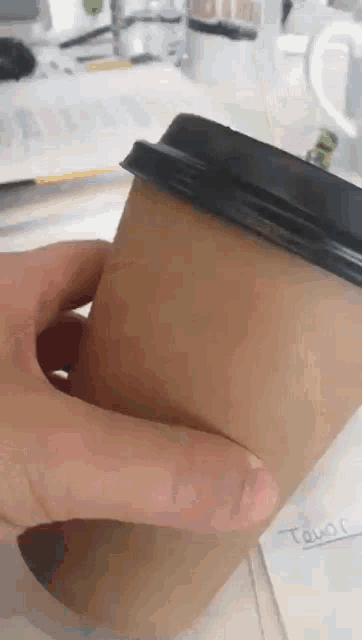 a close up of a person holding a coffee cup with the word town written on a piece of paper