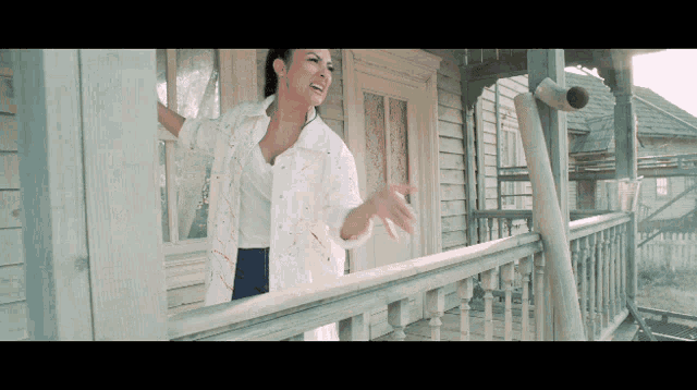 a woman in a white shirt is standing on a balcony
