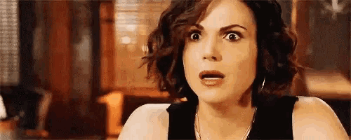 a woman with a surprised look on her face is wearing a black tank top .