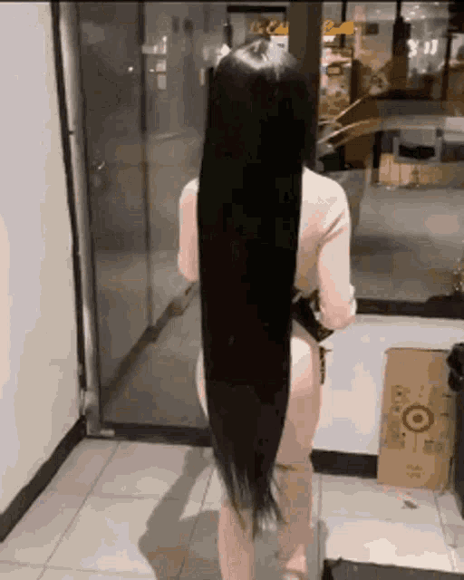 a woman with very long black hair is standing in front of a door