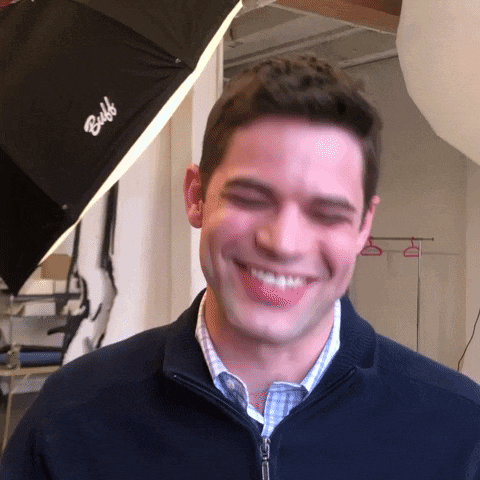 a man in a blue jacket smiles in front of a bulbo light