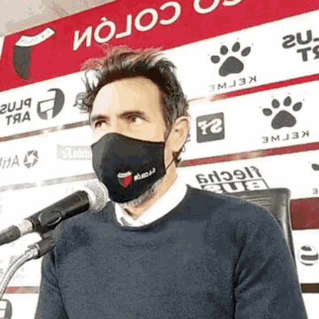 a man wearing a face mask is talking into a microphone .
