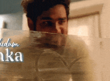 a man is peeking through a glass door with a heart etched on it .