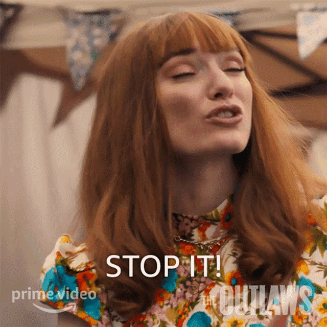 a woman with red hair is wearing a floral shirt and says stop it