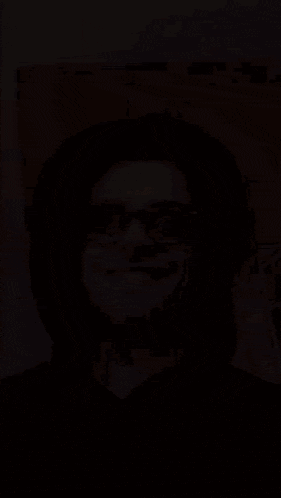 a man wearing glasses and a black hoodie is smiling .