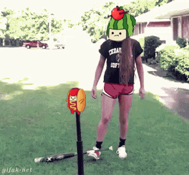 a girl wearing a watermelon hat is standing next to a hot dog and a bat