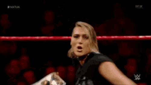 a woman in a ripley shirt is holding a wrestling championship