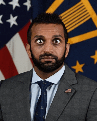 a man in a suit and tie is standing in front of a flag