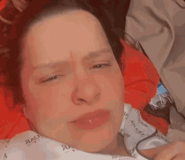 a woman in a hospital gown is laying on a bed making a funny face .