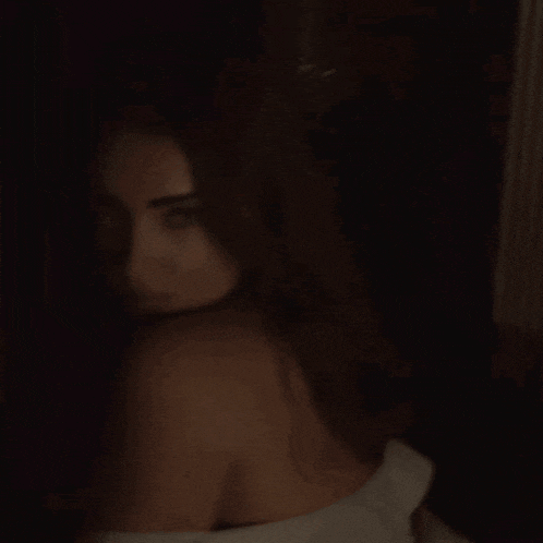 a woman is looking over her shoulder at the camera in a dark room