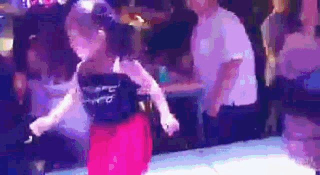 a woman in a red dress is dancing on a dance floor in a club .