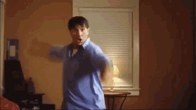 a man in a blue shirt is dancing in a room