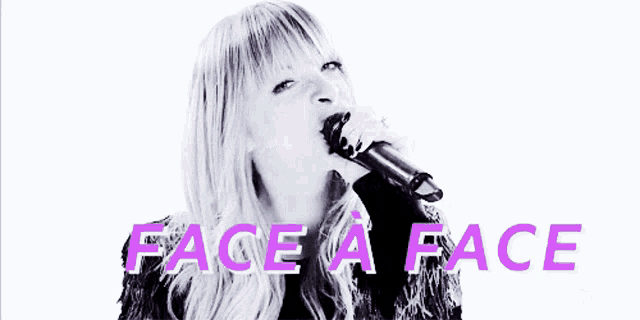 a woman singing into a microphone with face a face in purple letters