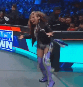 a woman in purple boots is dancing in front of a crowd at a wrestling match .